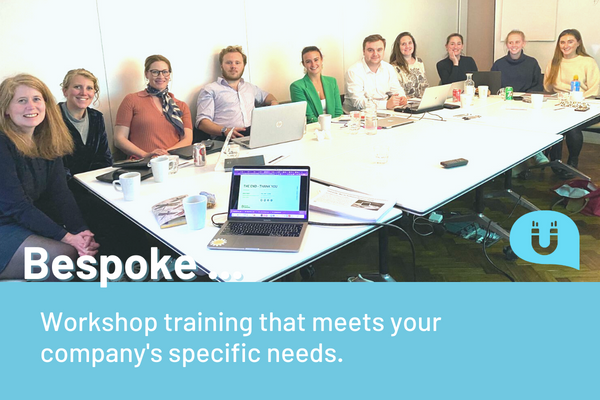 Bespoke training, Group of employees sat around a large table in a conference room. Laptops open and workbooks to hand.